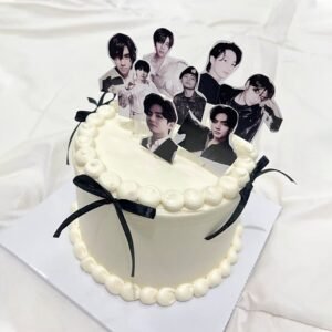 Minimalist white cream BTS theme birthday cake with black ribbon bows and member photo toppers, customized cake Karachi.